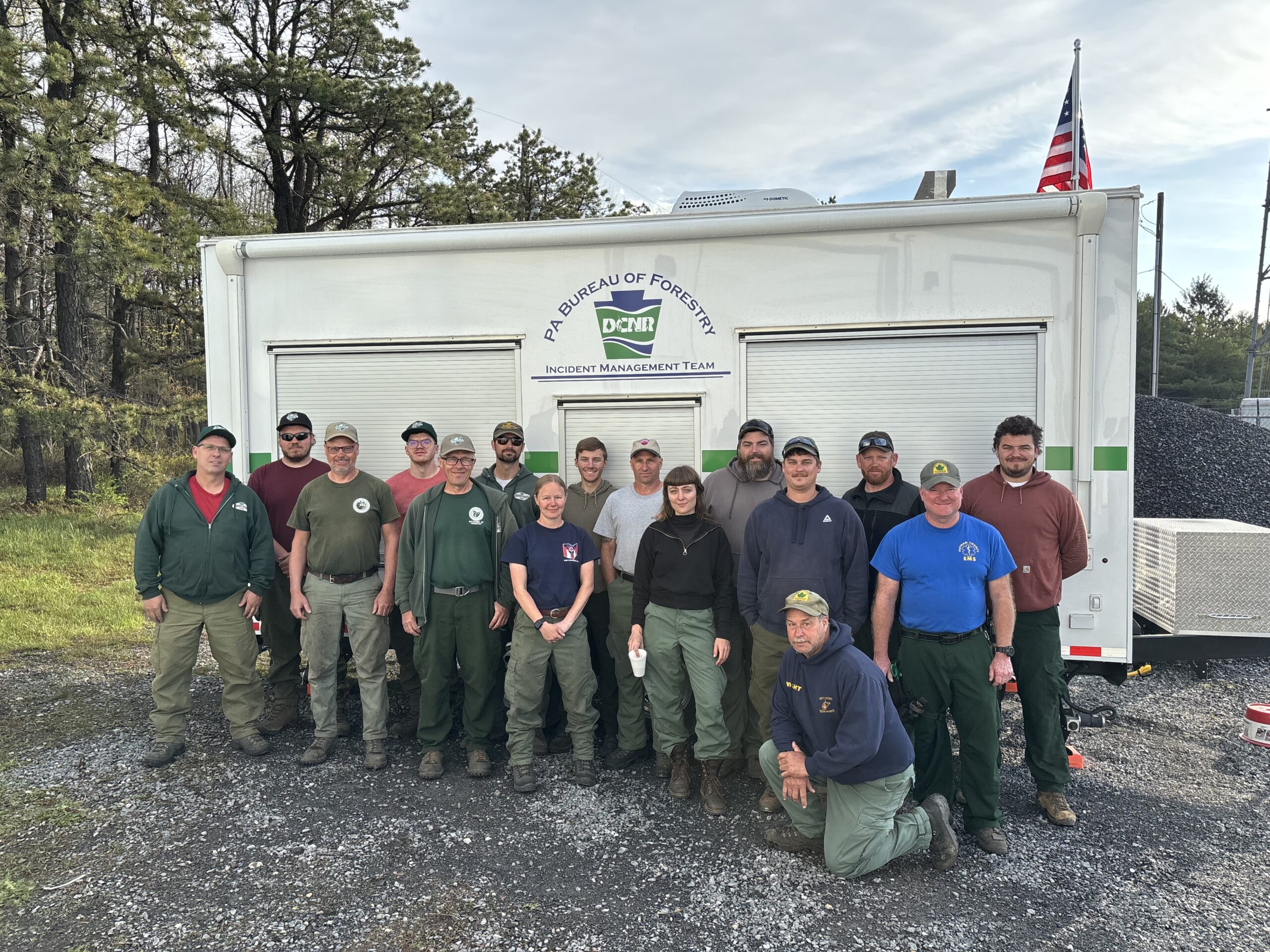 Wildland Fire Fighters from several states grouped in front of a Pennsylvania DCNR incident command trailer.