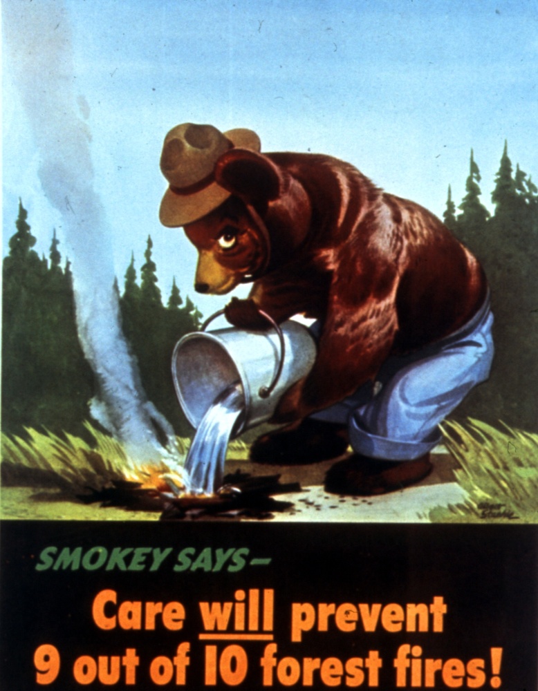 A black bear with a ranger hat and blue jeans pouring a bucket of water on a campfire. Text below: Smokey Says- Care will prevent 9 out of 10 forest fires!